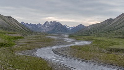 a vast valley with a river winding toward distant mountains at sunrise, no people, no text