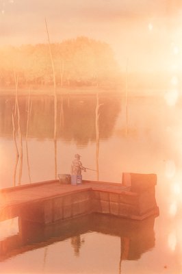 a man sitting on a dock with a fishing rod