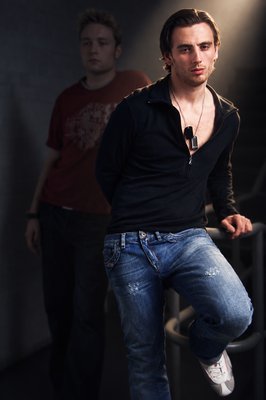 a man riding a skateboard while standing next to another man