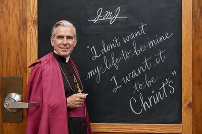 a priest standing in front of a blackboard