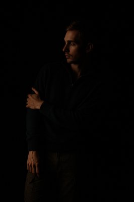 a man standing in the dark with his arms crossed