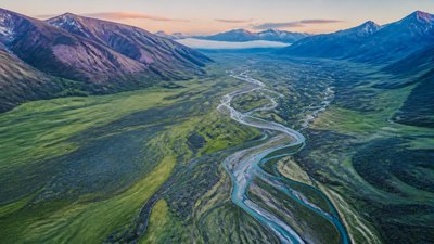 a vast valley with a river winding toward distant mountains at sunrise, no people, no text