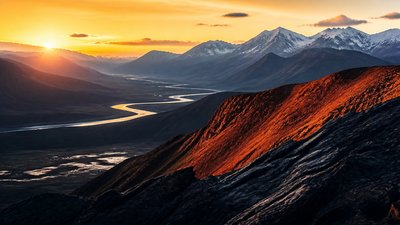 a vast valley with a river winding toward distant mountains at sunrise, no people, no text