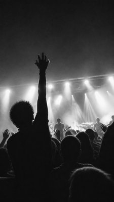 a live music scene with a glowing stage and silhouetted crowd, energetic vertical composition with open space at the top, no text