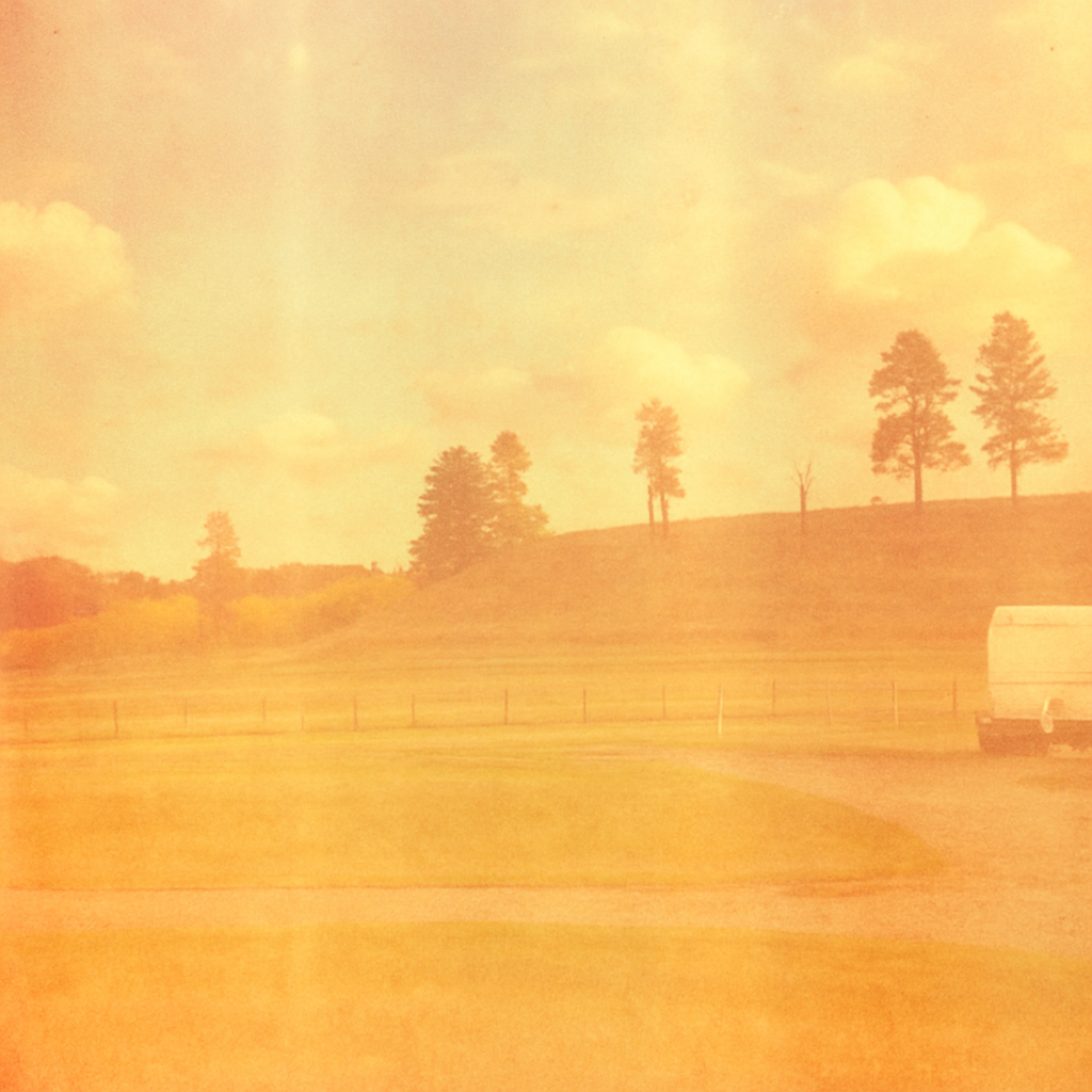 a white truck driving down a road next to a lush green field