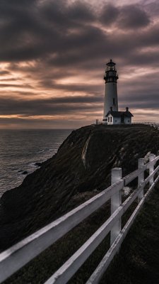a lone lighthouse on a cliff at dusk under a dramatic sky, no text or lettering