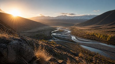 a vast valley with a river winding toward distant mountains at sunrise, no people, no text