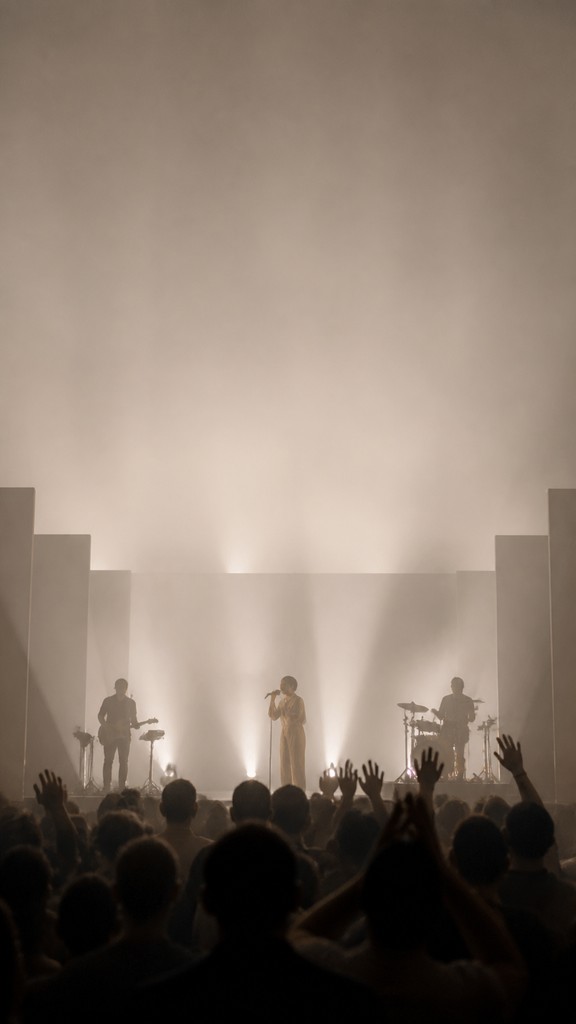 a live music scene with a glowing stage and silhouetted crowd, energetic vertical composition with open space at the top, no text
